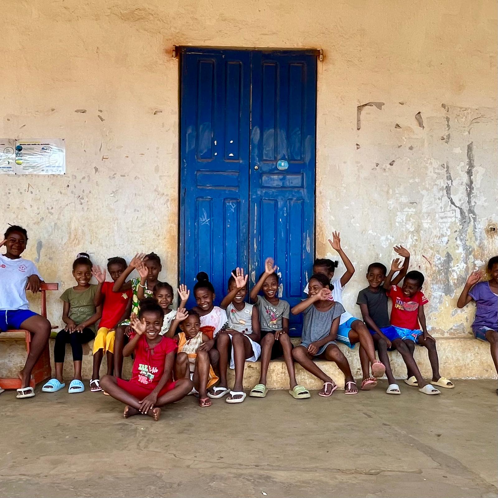 Children waving infront of blue door School in Madagascar