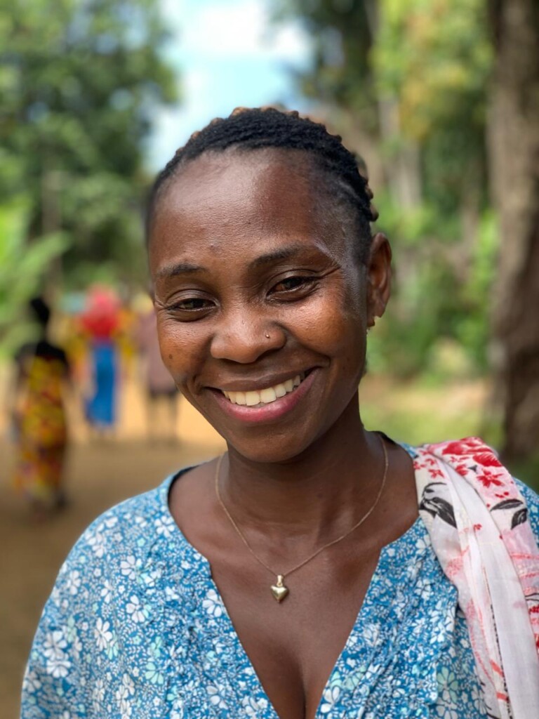 Madagascar a woman smiling, mother at a school, voluenteering for the canteen, other people in the background