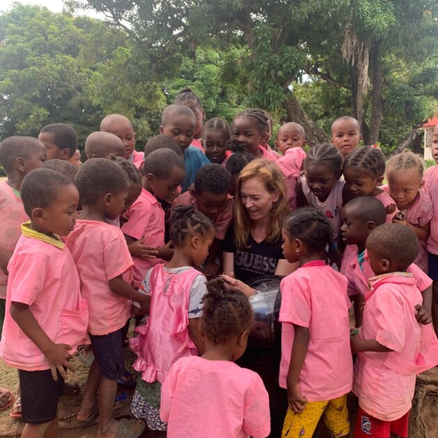 Volounteer with a group of pree school kids in the school yard, showing them the pictures she took of them, Madagascar