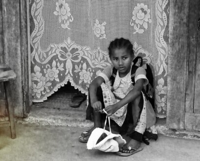 Picture of a young local girl sitting in the doorway to her house, waiting for the bus